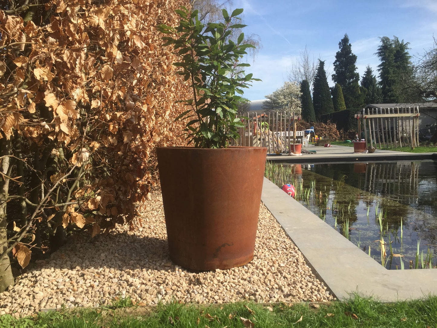 Weerbestendige cortenstaal plantenpot aan vijver