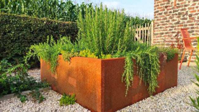 Roestkleurige plantenbak met groene planten