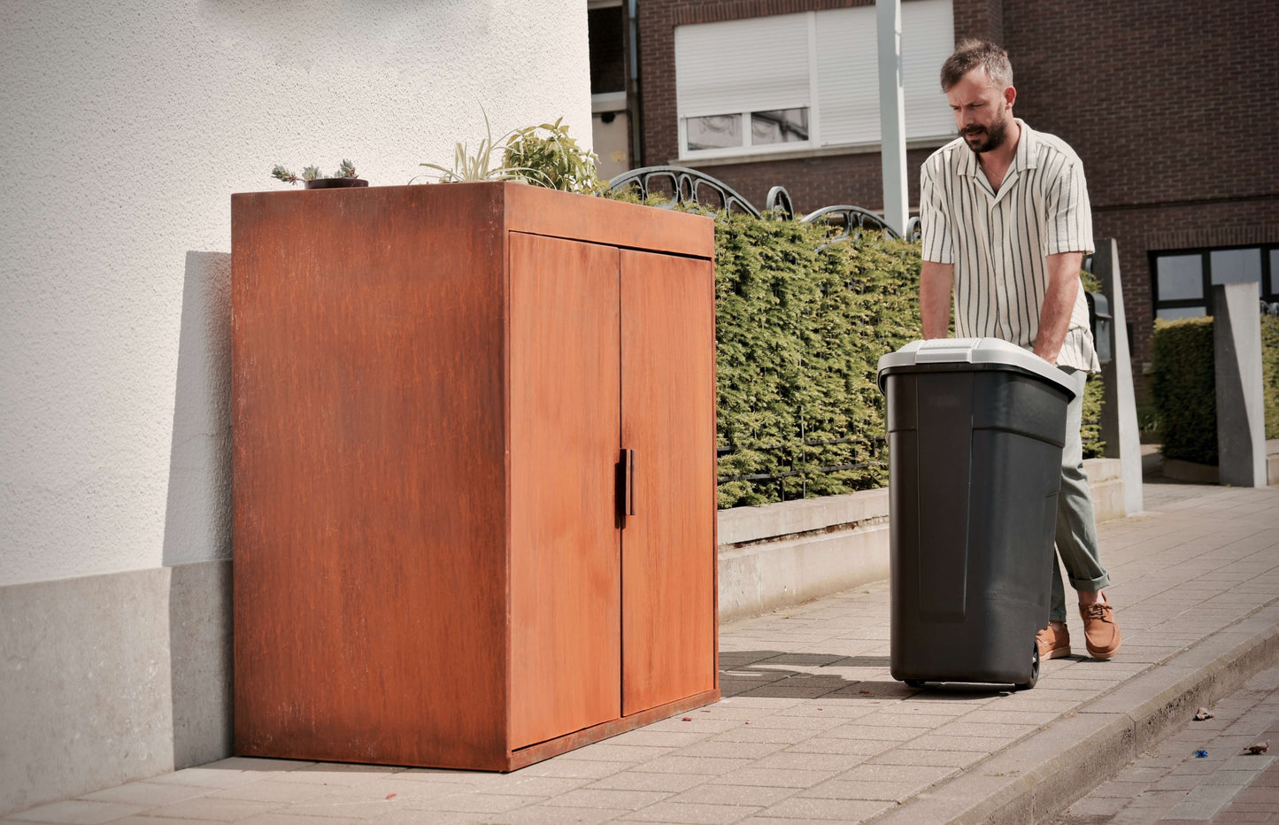 Man haalt kliko uit kliko ombouw van cortenstaal met plantenbak bovenop