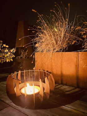 Sfeervolle vuurkorf of kaarsenhouder  op een houten terras met decoratieve planten