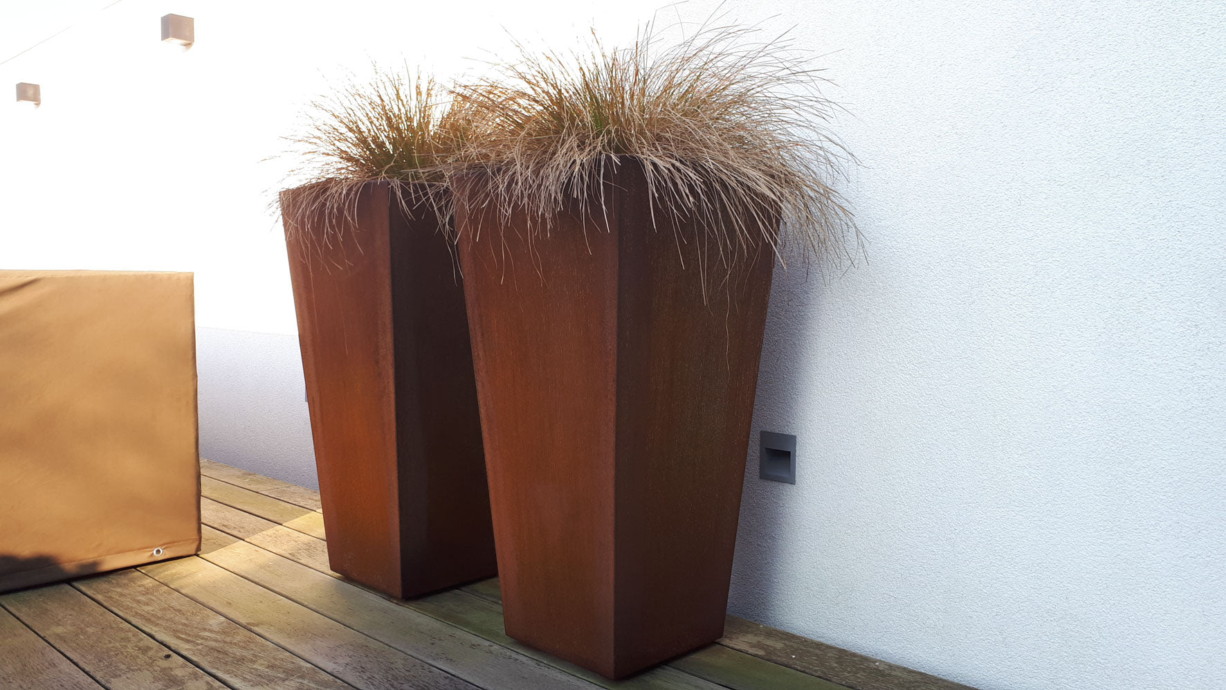 2 vaasvormige plantenbakken in cortenstaal met planten 