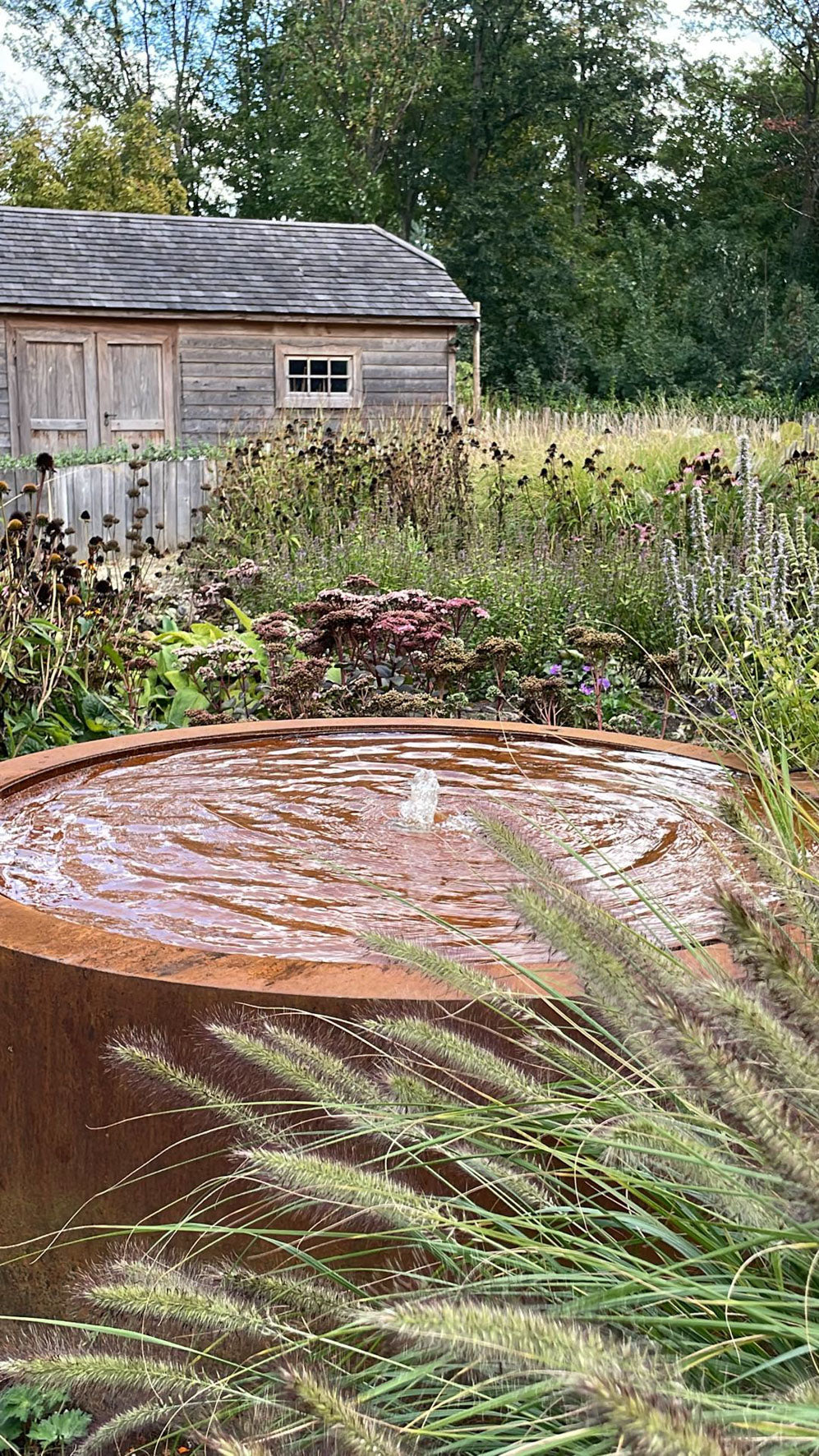 Watertafel met fonteintje in cortenstaal achter wuivende grassen
