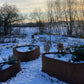 Organisch gevormde cortenstaal plantenbak in wintertuin met sneeuw en kippen – ORÉA collectie